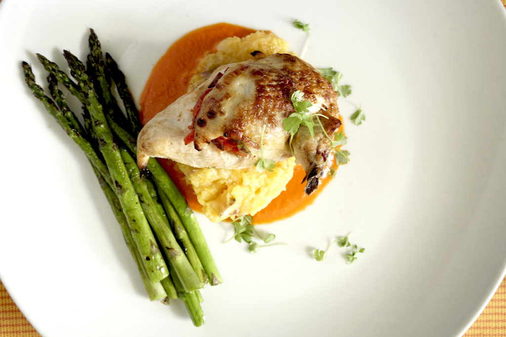 Peppadew Stuffed Chicken and Asparagus on a large white Plate with microgreens