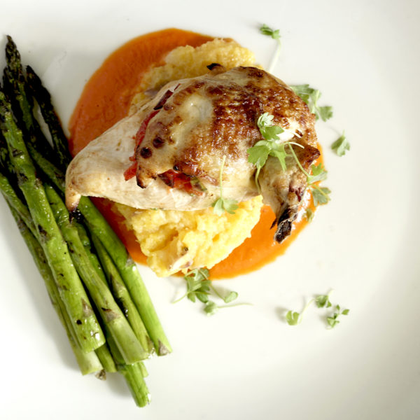 Peppadew Stuffed Chicken and Asparagus on a large white Plate with microgreens