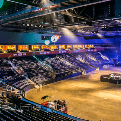 Inside at 1st Bank Center in the main concert area which is being prepared for a show. The seats are empty and lights are on. On stage lights are being tested.