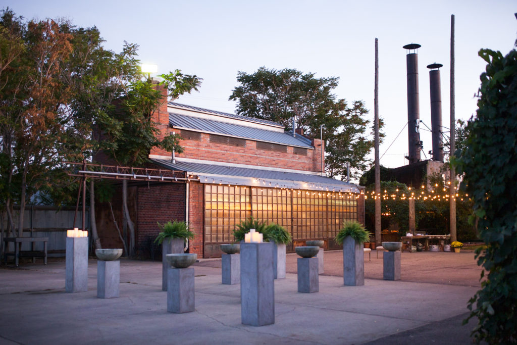 A red brick venue outside with a concrete patio with twinkle lights hanging above