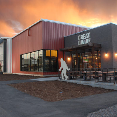 A large container like building with a sign reading "great divide' with a silhouette of a big food on the patio.