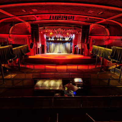 A large empty theatre with red and yellow lights on showcasing the the open floors and a large stage
