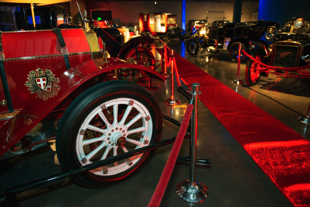 Inside the vechile vault with a red carpet and old automobiles everywhere