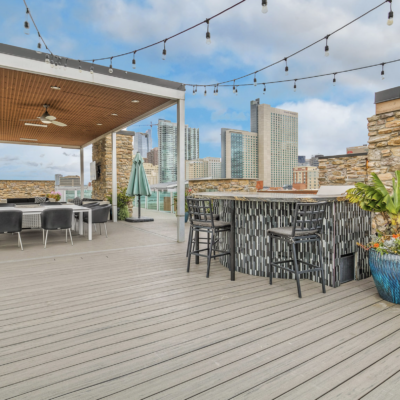 Outdoor rooftop patio at 360 at Skyline with a pergola with black chairs and white tables and a dark bar with black barstools.
