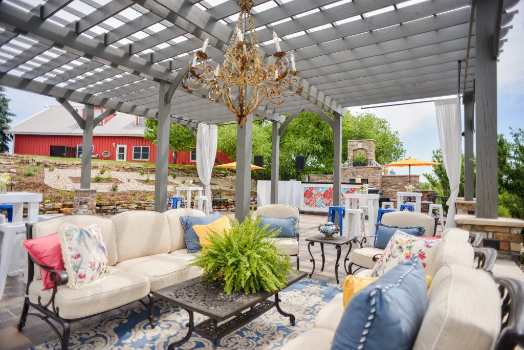 Light cream lounge outdoor furniture with bright colored pillows under a grey painted pergola
