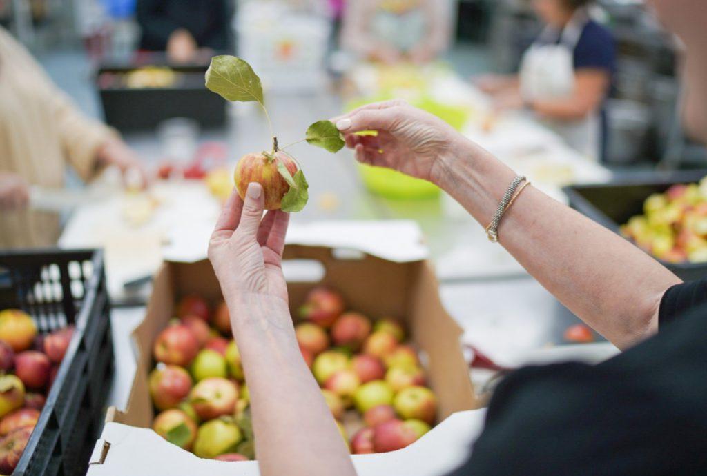 A hand picking a apple out of a box