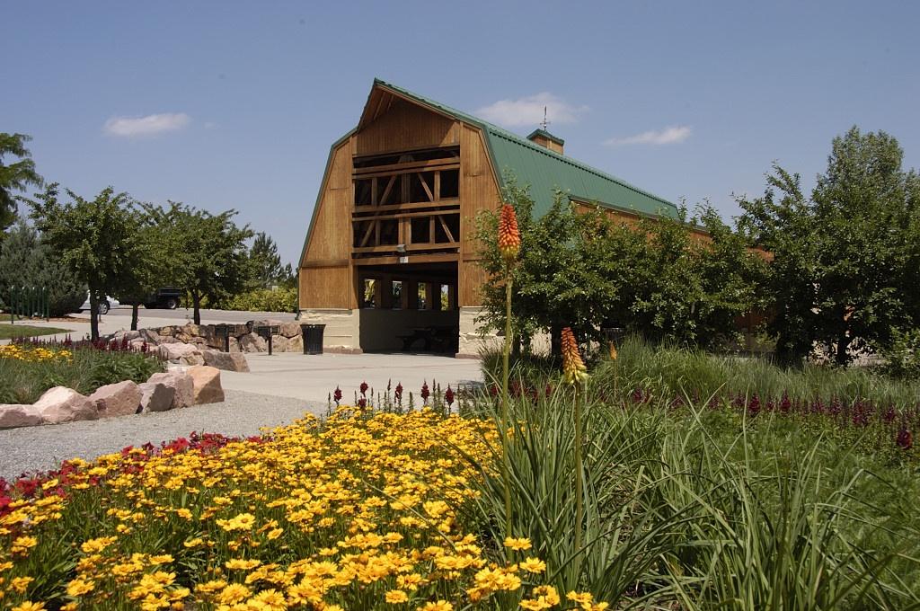 A barn in Silo Park during nice weather with lots of flowers and greenery around