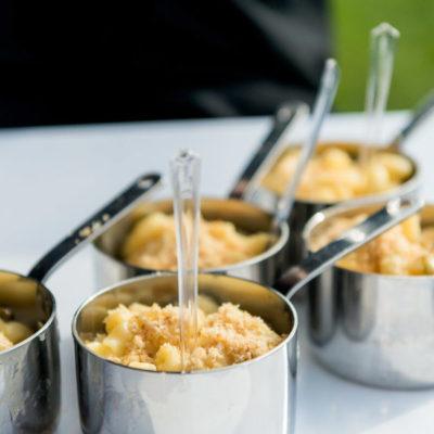 Mac and cheese in small pots with a plastic fork in the mac and cheese