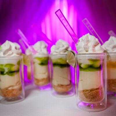 Key Lime Pie Shooters in small containers with a purple neon background