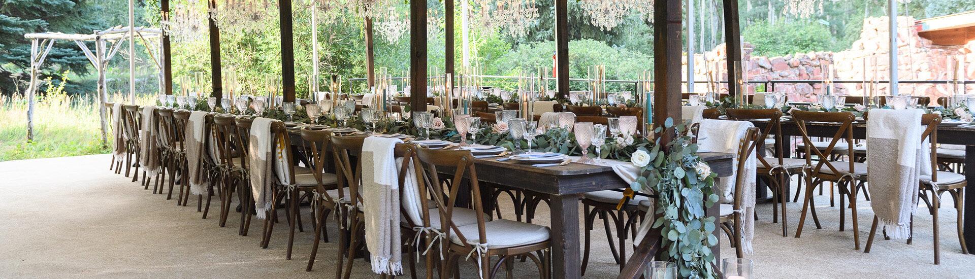 Wooden tables next to each outer with greenery on the tables