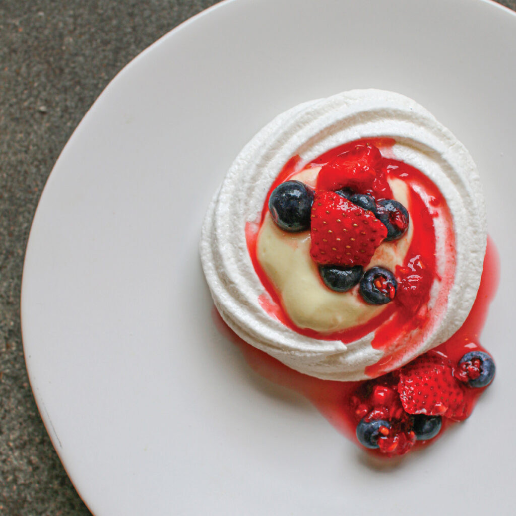Pavlova filled with custard and fresh berries.