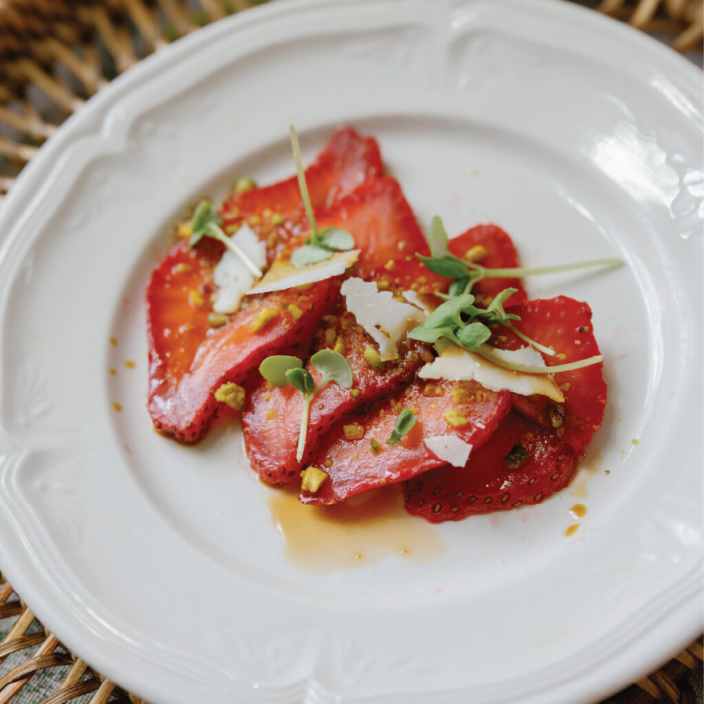Thinly sliced strawberries on a white plate with parmesan and