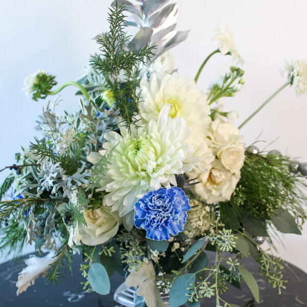 Winter floral arrangement with white, blue, green and silver floral elements