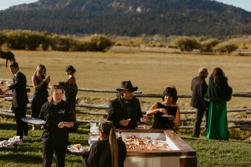 Guests enjoying a seafood raw bar during an outdoor cocktail hour with mountain views.